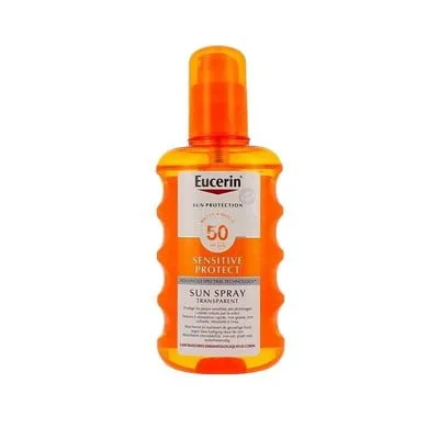 Un flacon de spray solaire Eucerin Sensitive Protect avec un fond de plage ensoleillée, symbolisant une protection efficace et sûre pour tous, des enfants aux adultes, contre les rayons UV