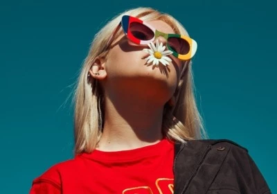 Une fille à la mode portant des lunettes et une fleur dans la bouche